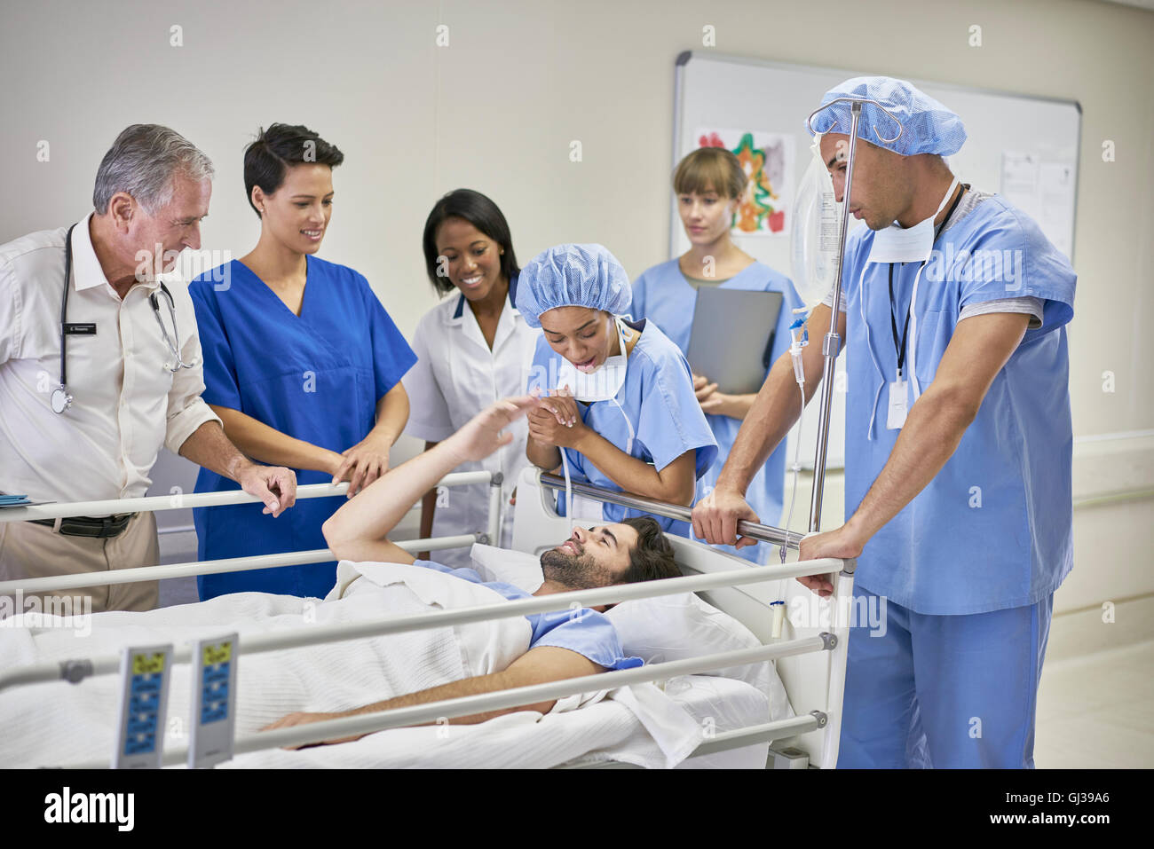 Ärzte und Krankenschwestern um Patienten im Krankenhausbett Stockfoto