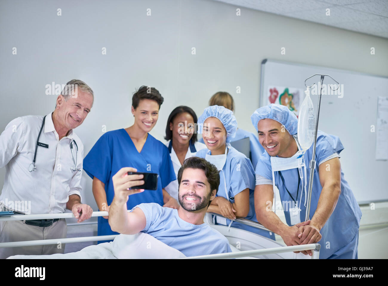 Patienten im Krankenhausbett nehmen Selfie mit Ärzten und Krankenschwestern Stockfoto