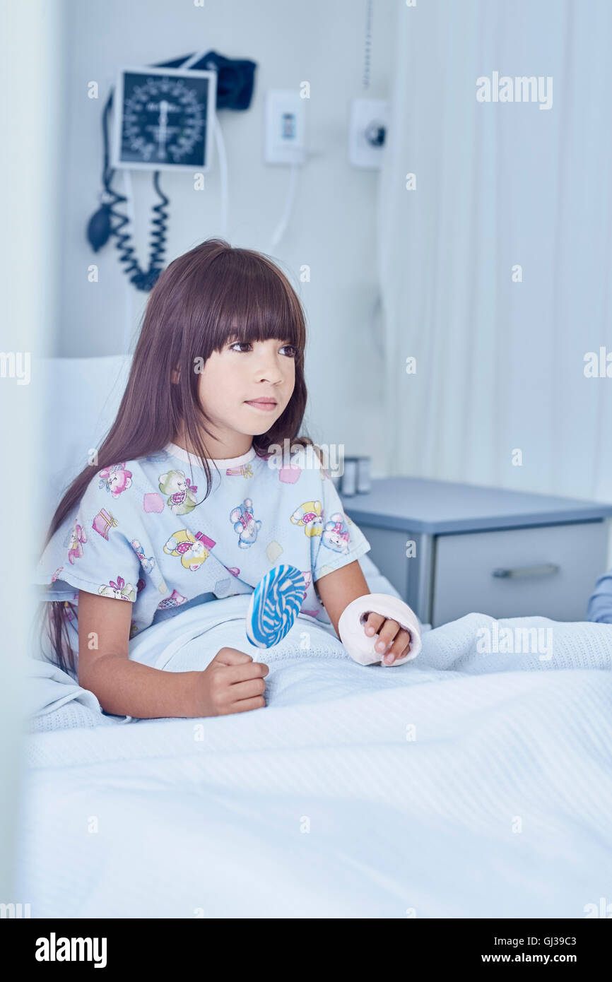 Mädchen-Patient mit Gips Arm im Bett mit Lollipop im Krankenhaus Kinderstation Stockfoto