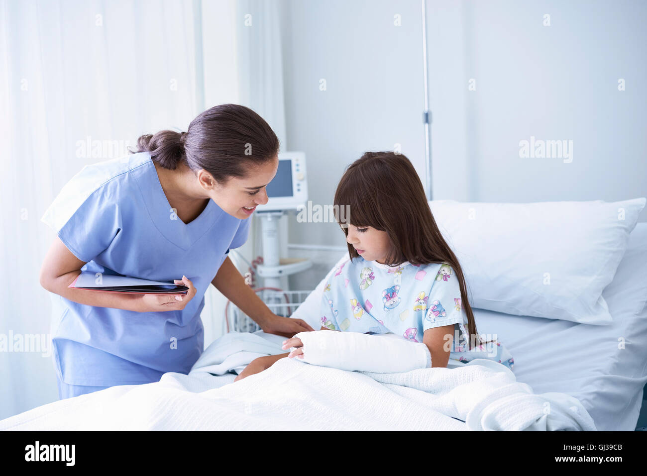 Krankenschwester, Mädchen Patient mit Gips Arm im Krankenhaus Kinderstation zu erklären Stockfoto
