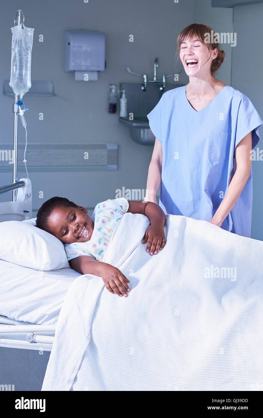 Krankenschwester mit Mädchen Patient im Bett im Krankenhaus Kinderstation lachen Stockfoto