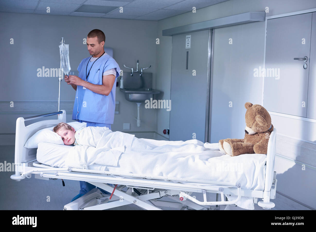 Krankenpfleger, die Anpassung der intravenösen Tropf für junge Patienten im Krankenhaus Kinderstation Stockfoto