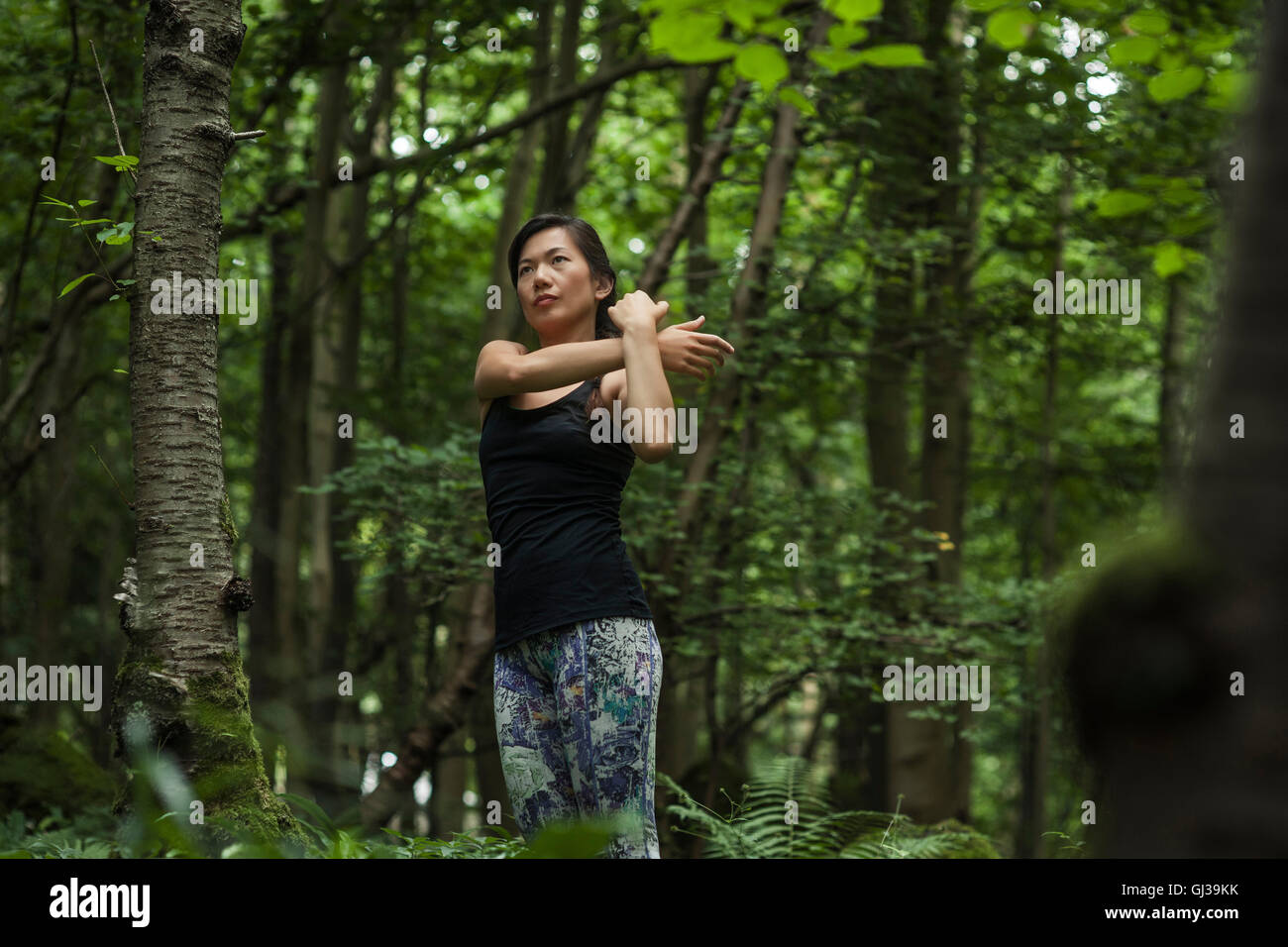 Mitte Erwachsene Frau im Wald trainieren, stretching Stockfoto