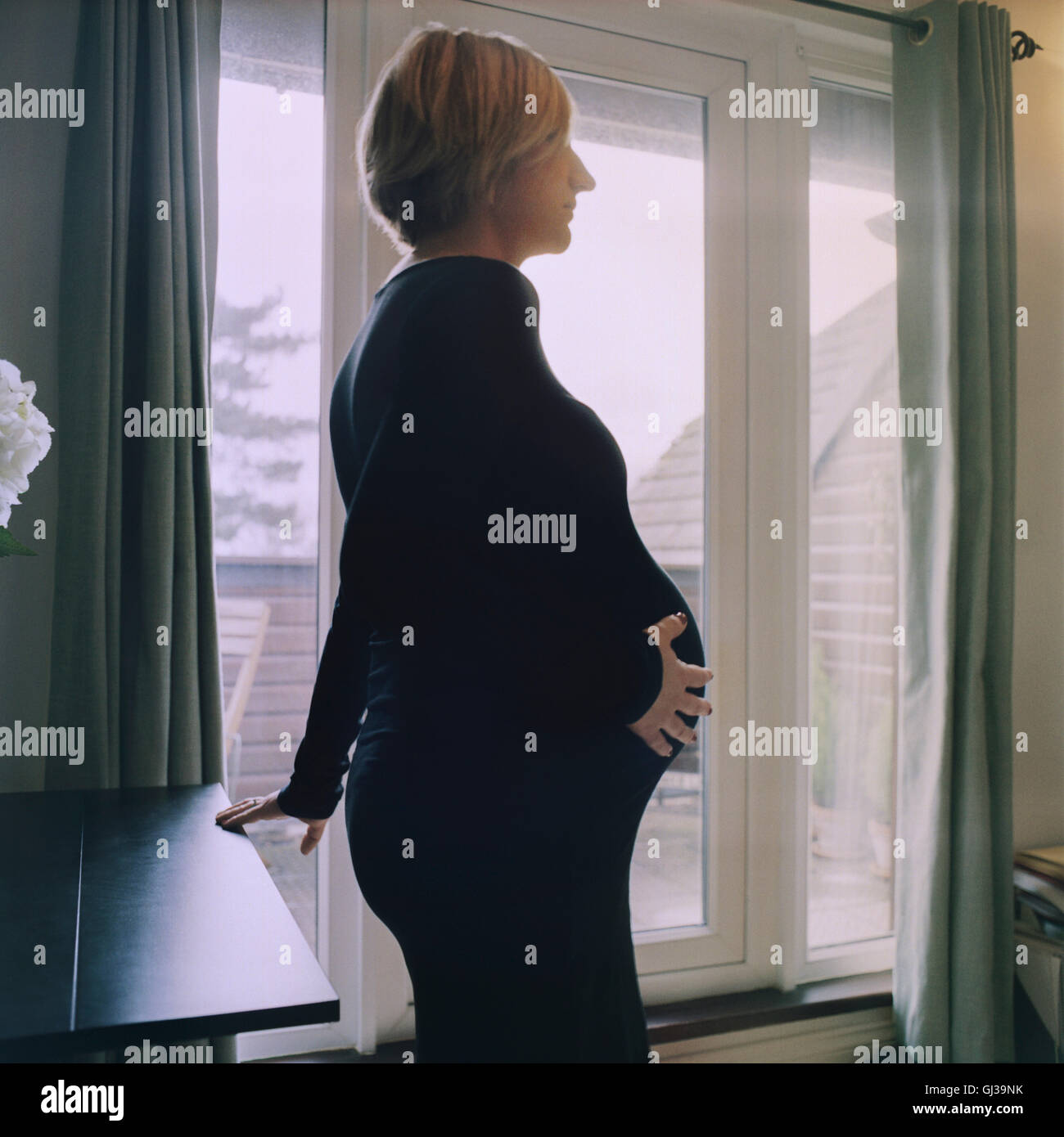 Seitenansicht der schwangeren Frau mit Hand auf Bauch Stockfoto
