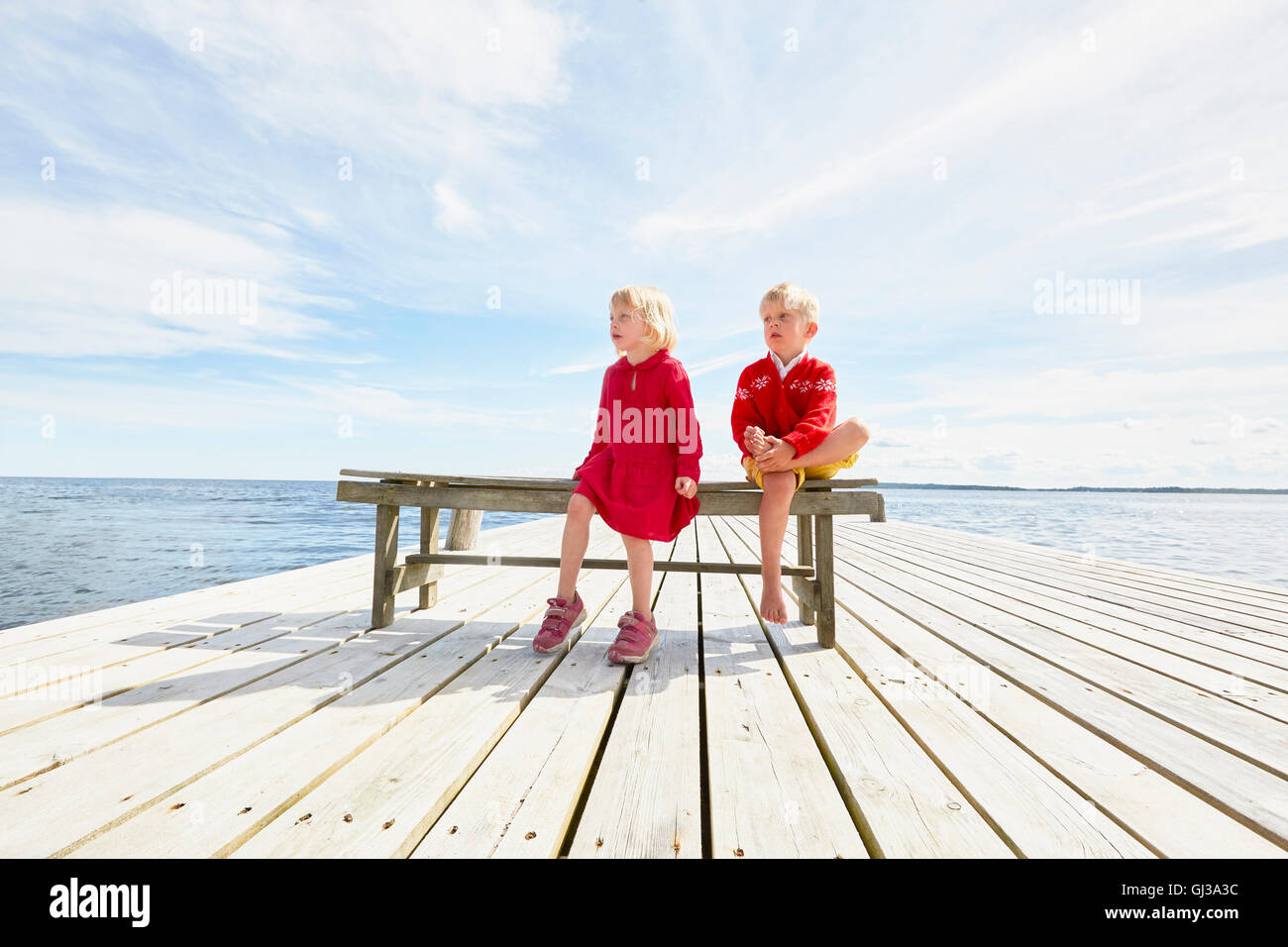 Zwei junge Freunde sitzen auf Bank auf hölzerne pier Stockfoto