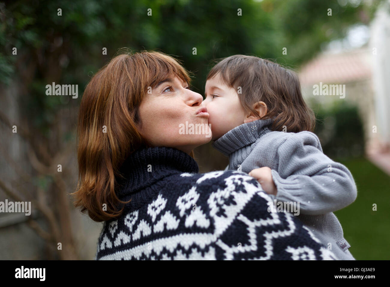 Mutter und Tochter auf Wange küssen Stockfoto