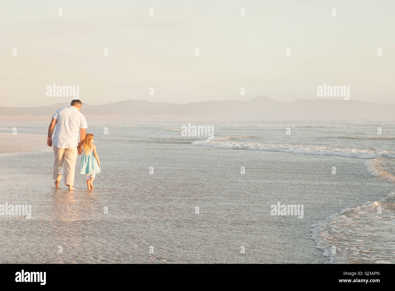 Vater und Tochter, die Hand in Hand Paddeln im Ozean Stockfoto