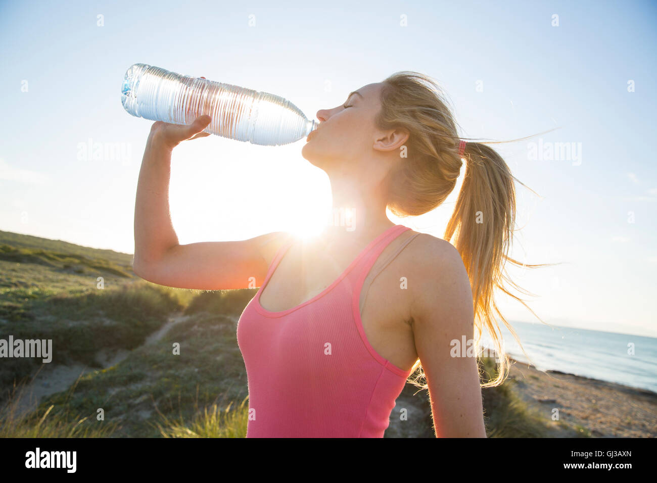 Junge Frau am Strand, trinken aus der Flasche Wasser Stockfoto