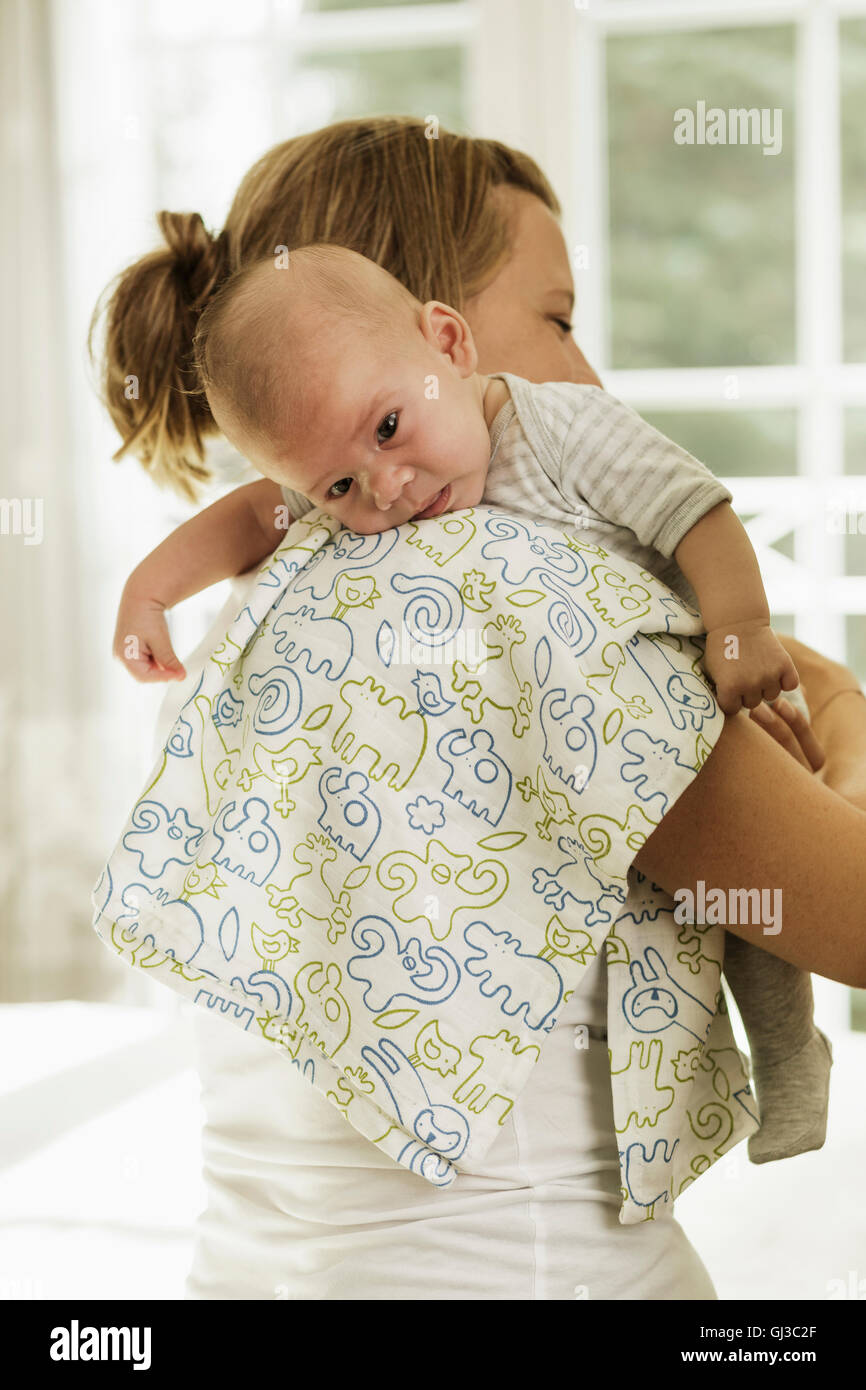 Aufstoßen Baby Sohn Mutter, während ihm auf die Schulter zu tragen Stockfoto
