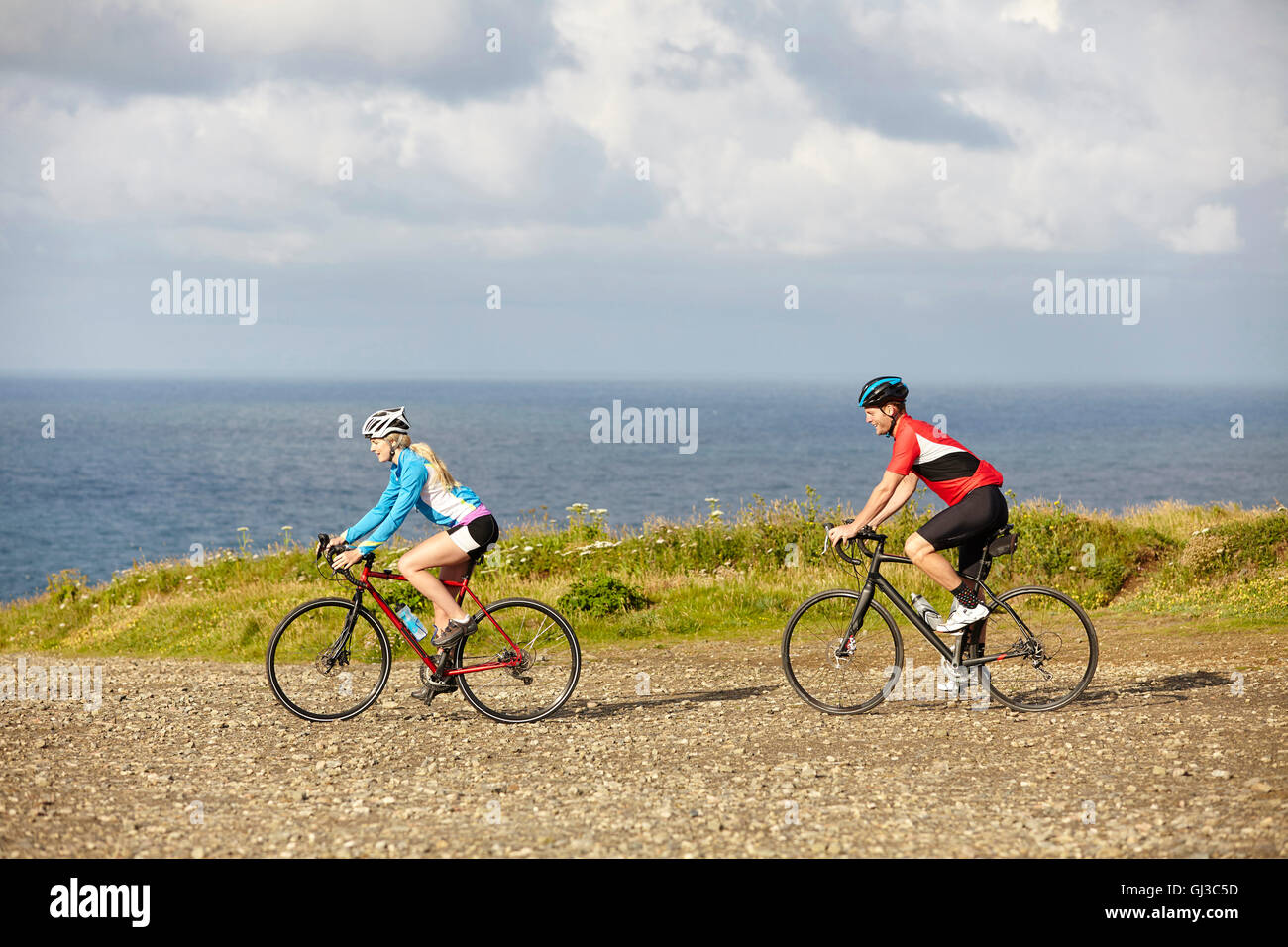 Radfahrer fahren auf Schotterstraße mit Blick auf Meer Stockfoto