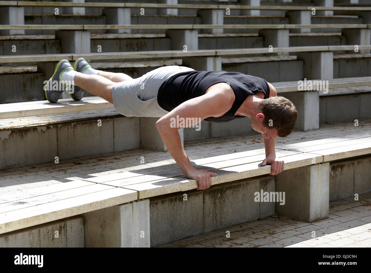Junger Mann training, tut Push ups auf Stadion-Treppe Stockfoto