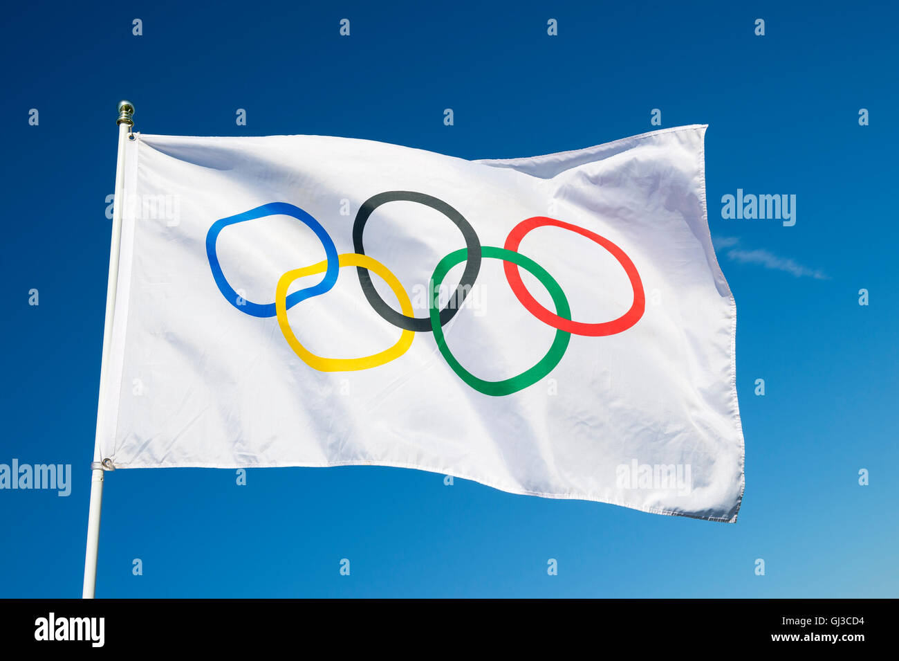 RIO DE JANEIRO - 27. März 2016: Eine olympische Fahne flattert im Wind gegen strahlend blauen Himmel. Stockfoto