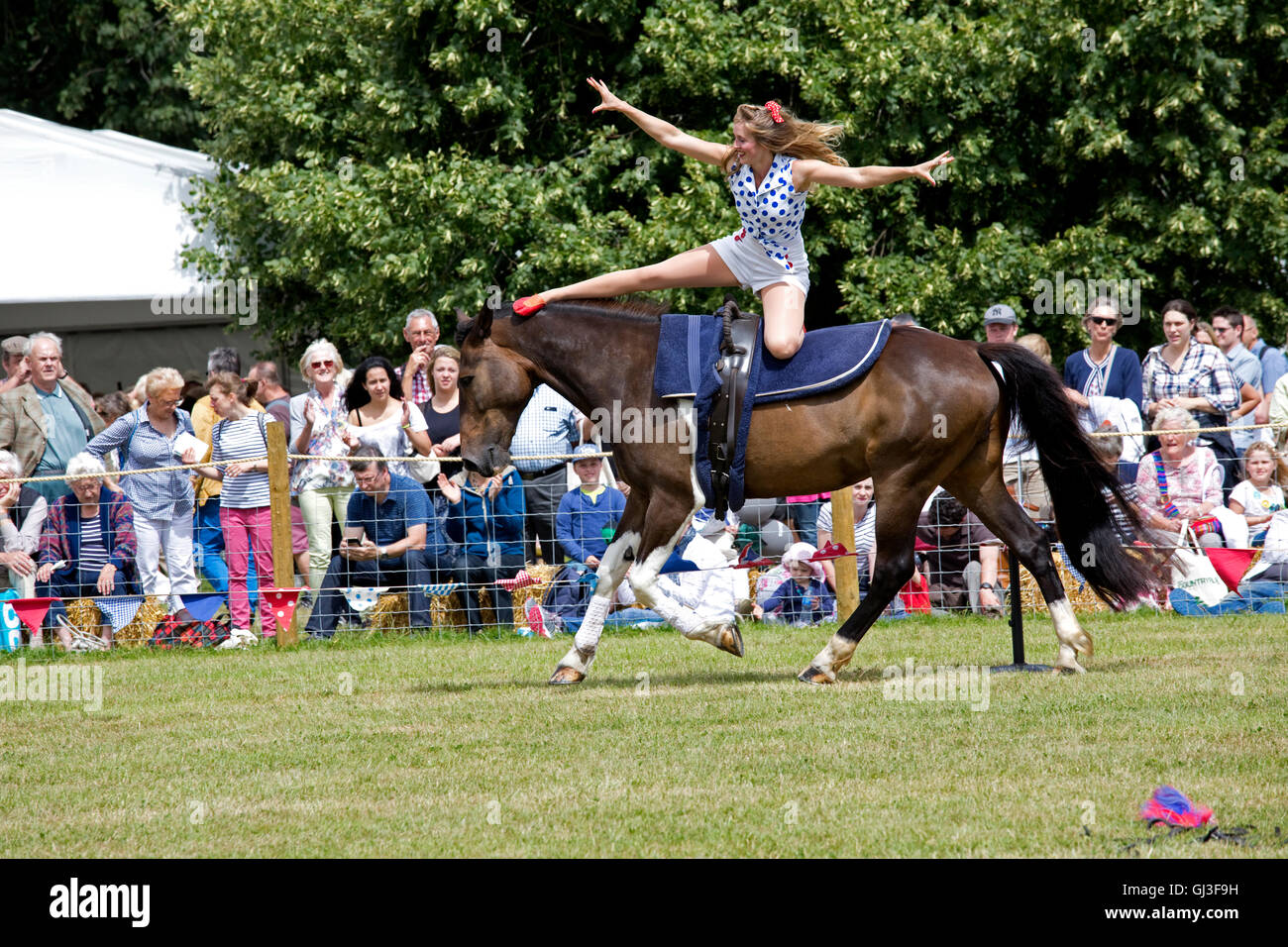 Massen-Uhr lächelndes Mädchen darstellende Akrobatik auf Rückseite galoppierenden Pferd Galloping Akrobatik Countryfile Live Blenheim UK Stockfoto