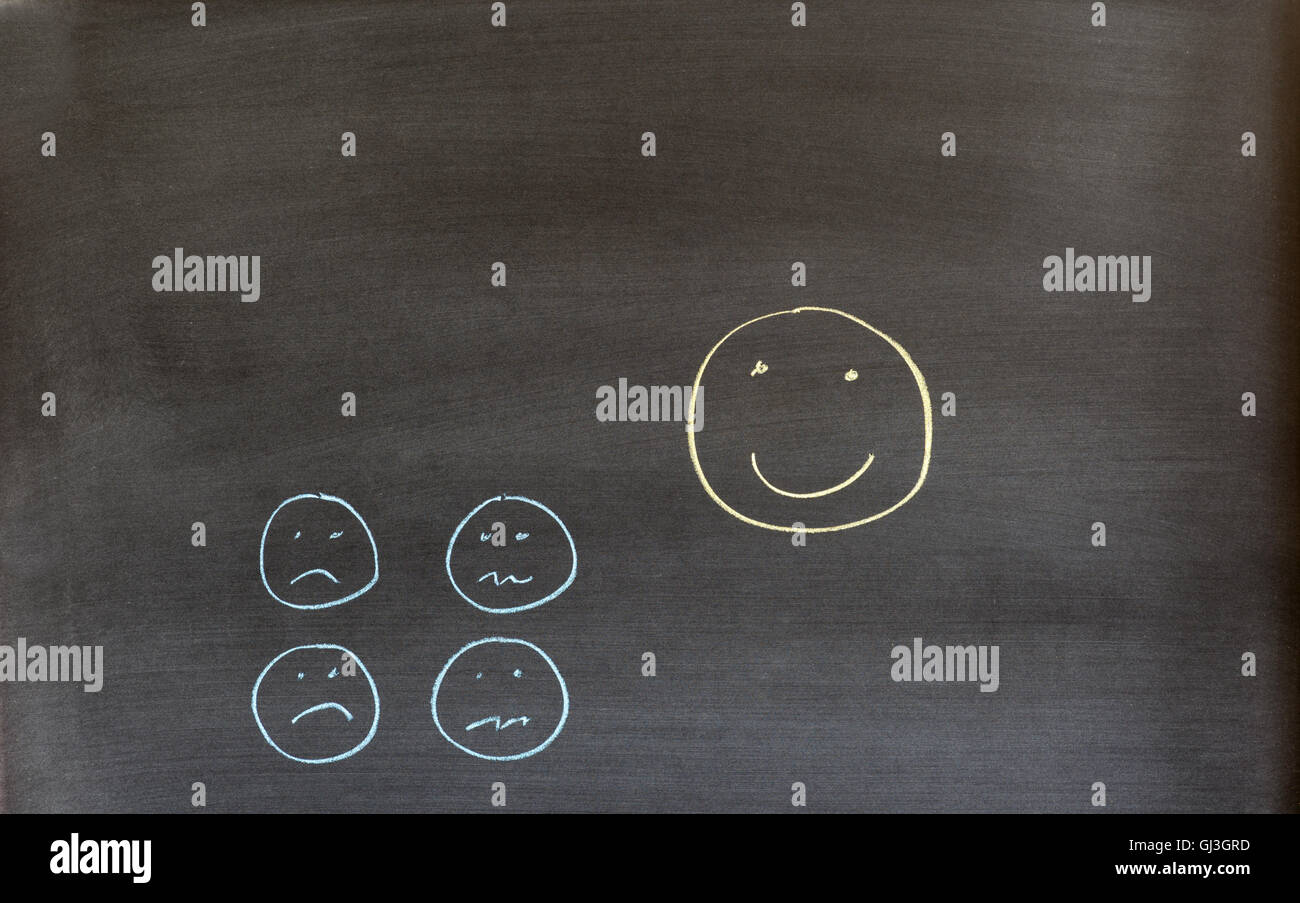 Smiley-Gesicht und Gesichter mit Stirnrunzeln auf einer Tafel gezeichnet. Stockfoto