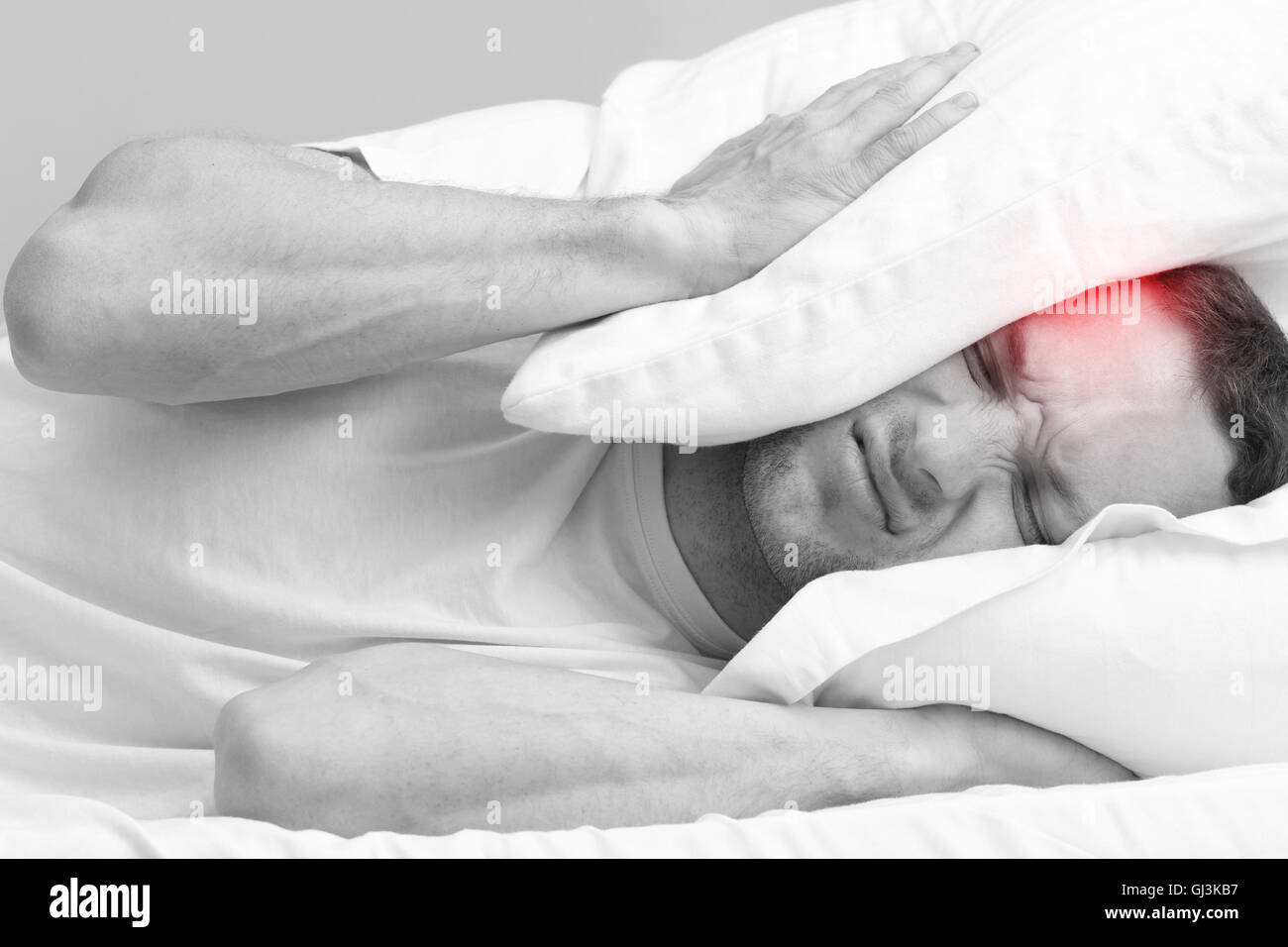 Porträt von wütenden jungen Mann im Bett mit starken Kopfschmerzen. Stilisierte Foto schwarz / weiß mit roten lokalen Schmerzen vor Ort Stockfoto