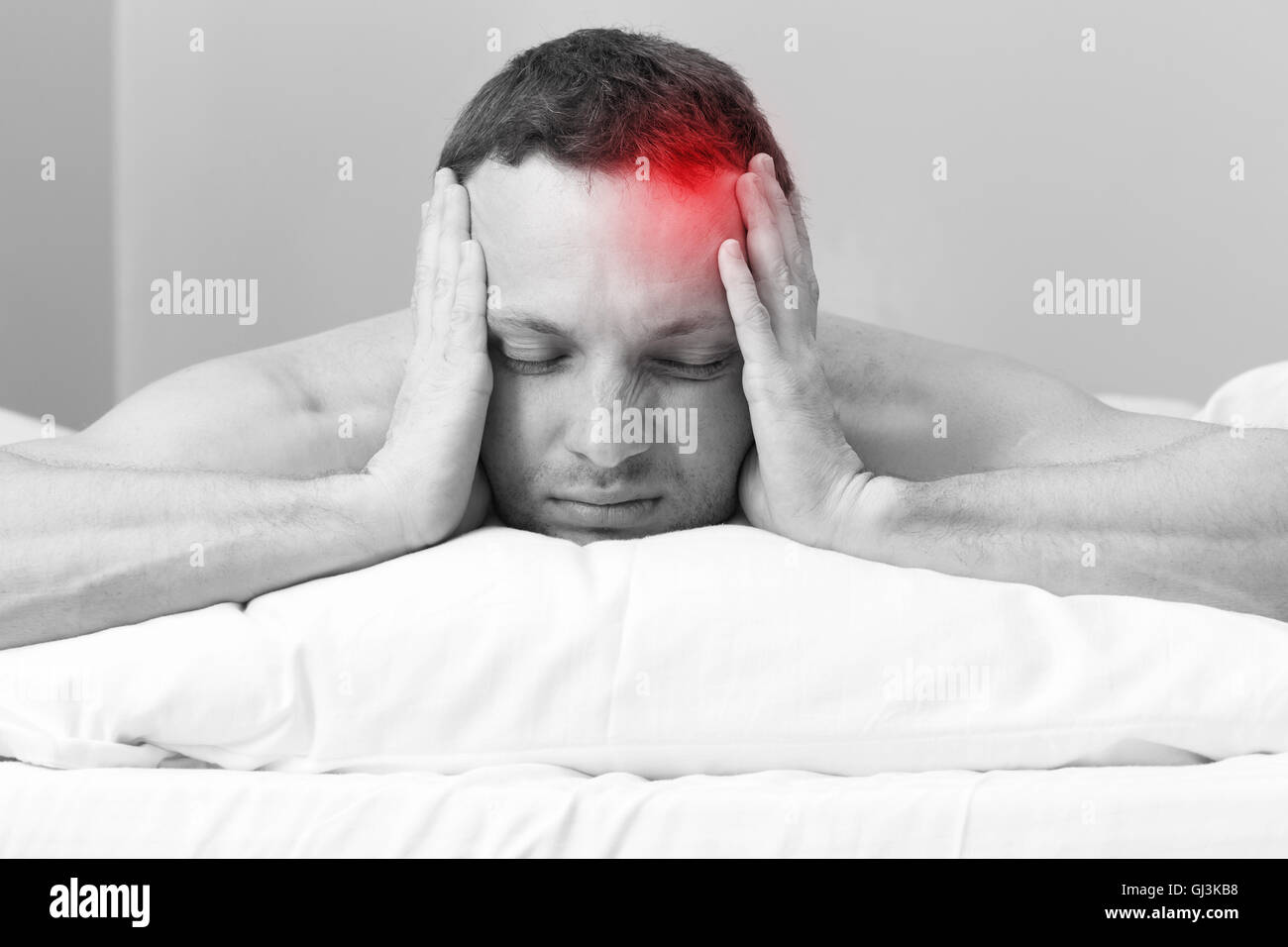 Porträt des jungen Mann im Bett mit Kopfschmerzen. Stilisierte Foto schwarz / weiß mit roten lokalen Schmerzen vor Ort Stockfoto