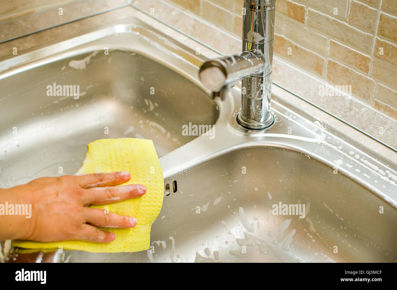 Schwamm gelb sauber Wasserhahn Spüle Aufgaben die Zimmermädchen die Hand Stockfoto