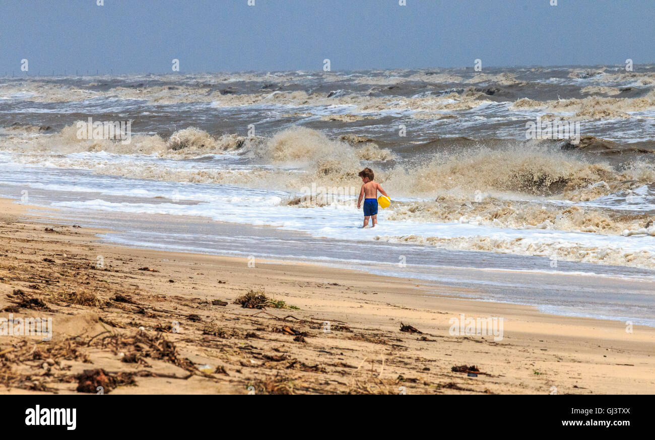 Kleiner Junge spielt in raue Brandung bei einem windigen Tag am Rutherford Strand an der Küste des Golfs von Mexiko in Louisiana. Stockfoto
