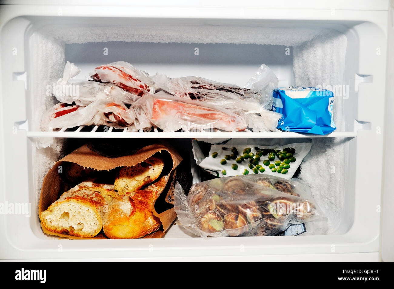 Gefrierfach eines Kühlschranks mit Fleisch sowie gefrorenes Gemüse und Brot Stockfoto