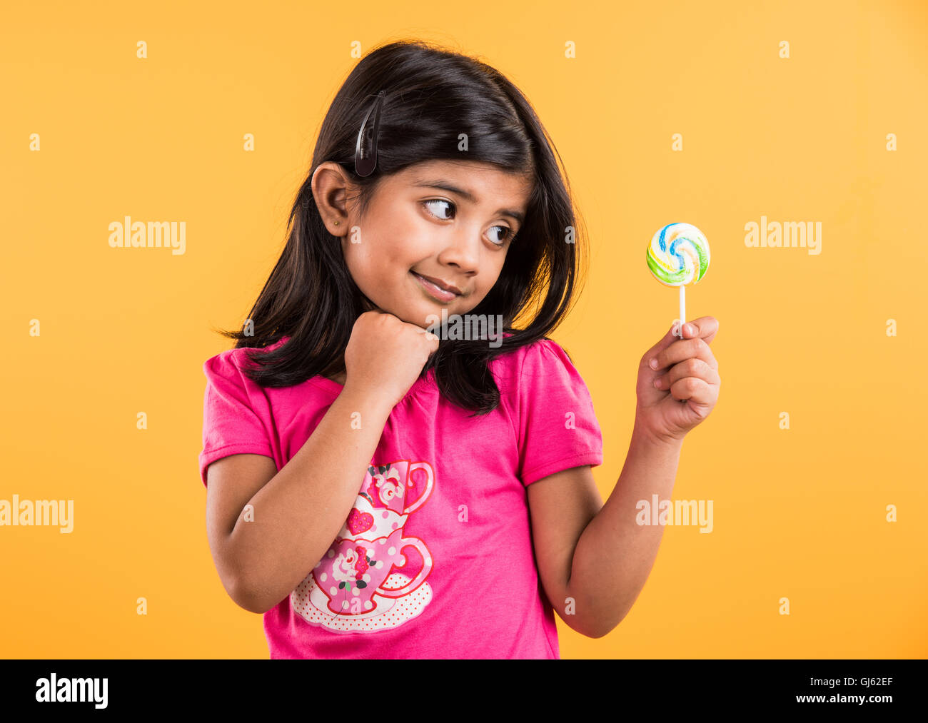 kleine Inderin mit Lolipop oder Loly Pop, Asiatin und Lolipop Lolypop, verspielte süße Inderin posiert mit lolipop Stockfoto