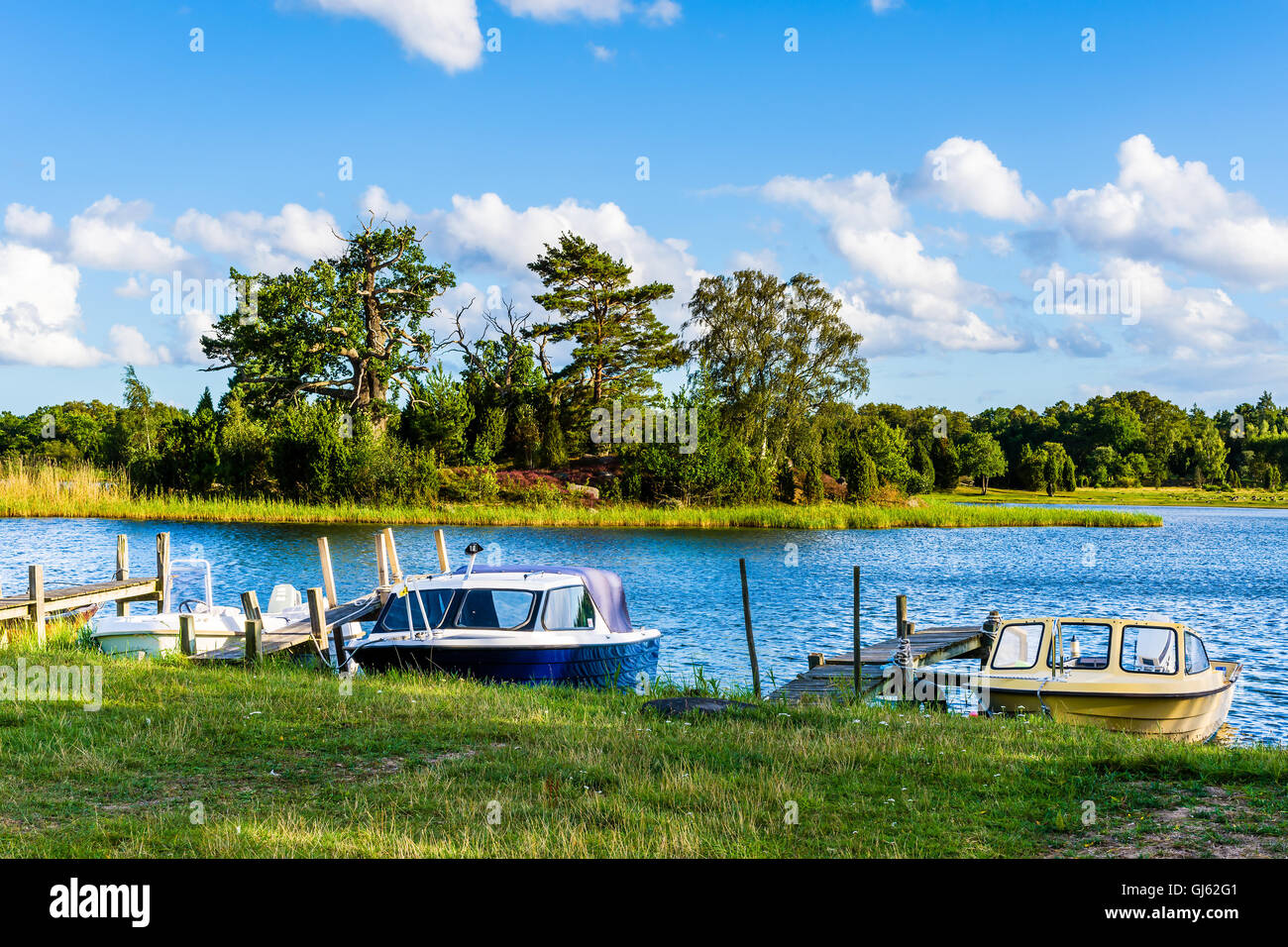 Pataholm, Schweden - 9. August 2016: Drei Freizeitboote vertäut an improvisierten Piers in einer wunderschönen natürlichen Umgebung in der archi Stockfoto