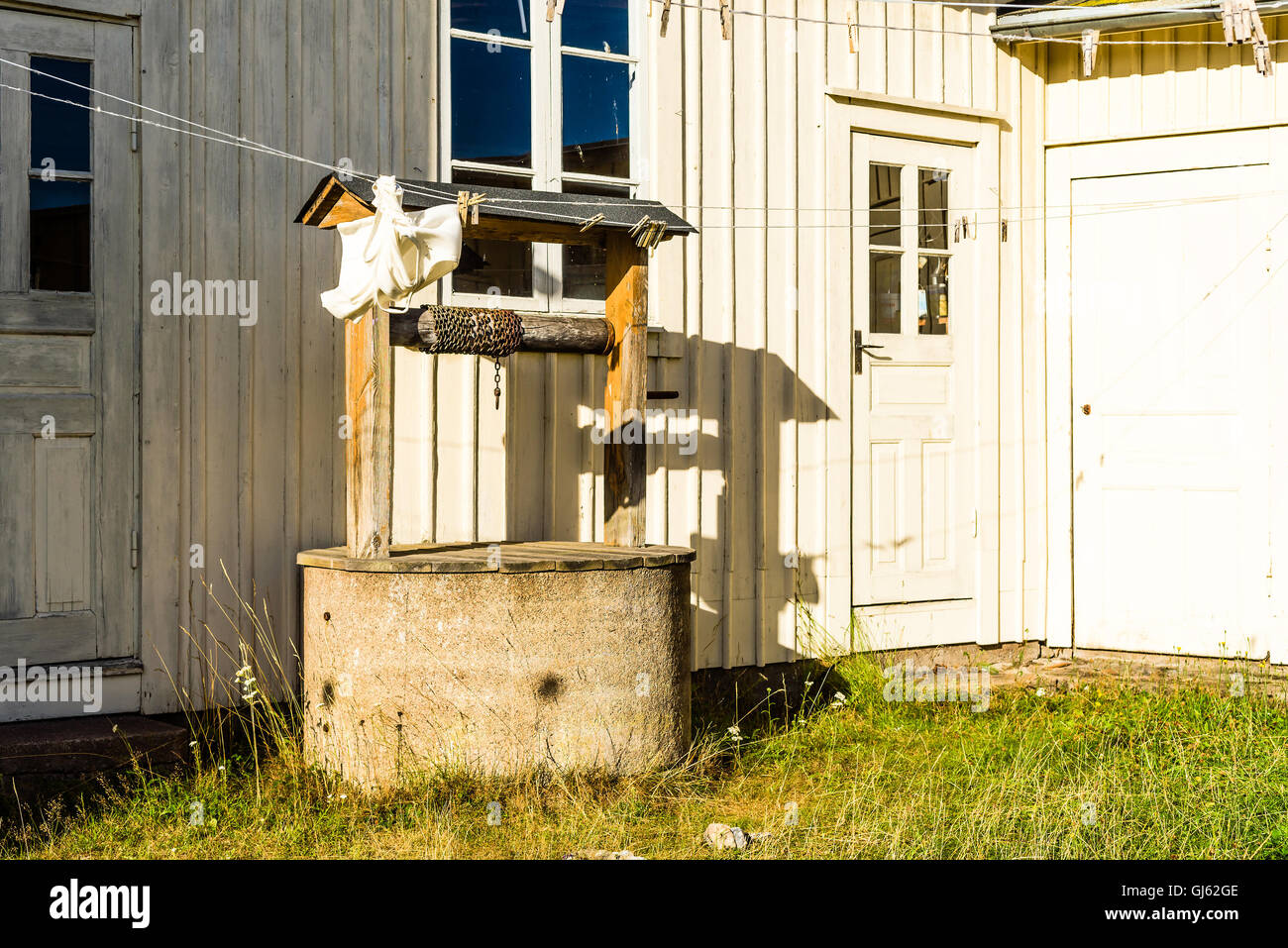 Alte Wassermühle mit rostigen Kette ganz in der Nähe des Hauses. Klein und alt Garten mit Outdoor-Schuppen. Stockfoto