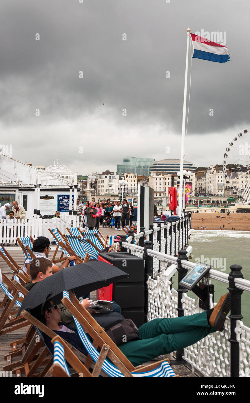 Personen in Liegestühlen und einer französischen Flagge, die am Pier von Brighton, Brighton, East Essex, Großbritannien, ab 2012 fliegt Stockfoto