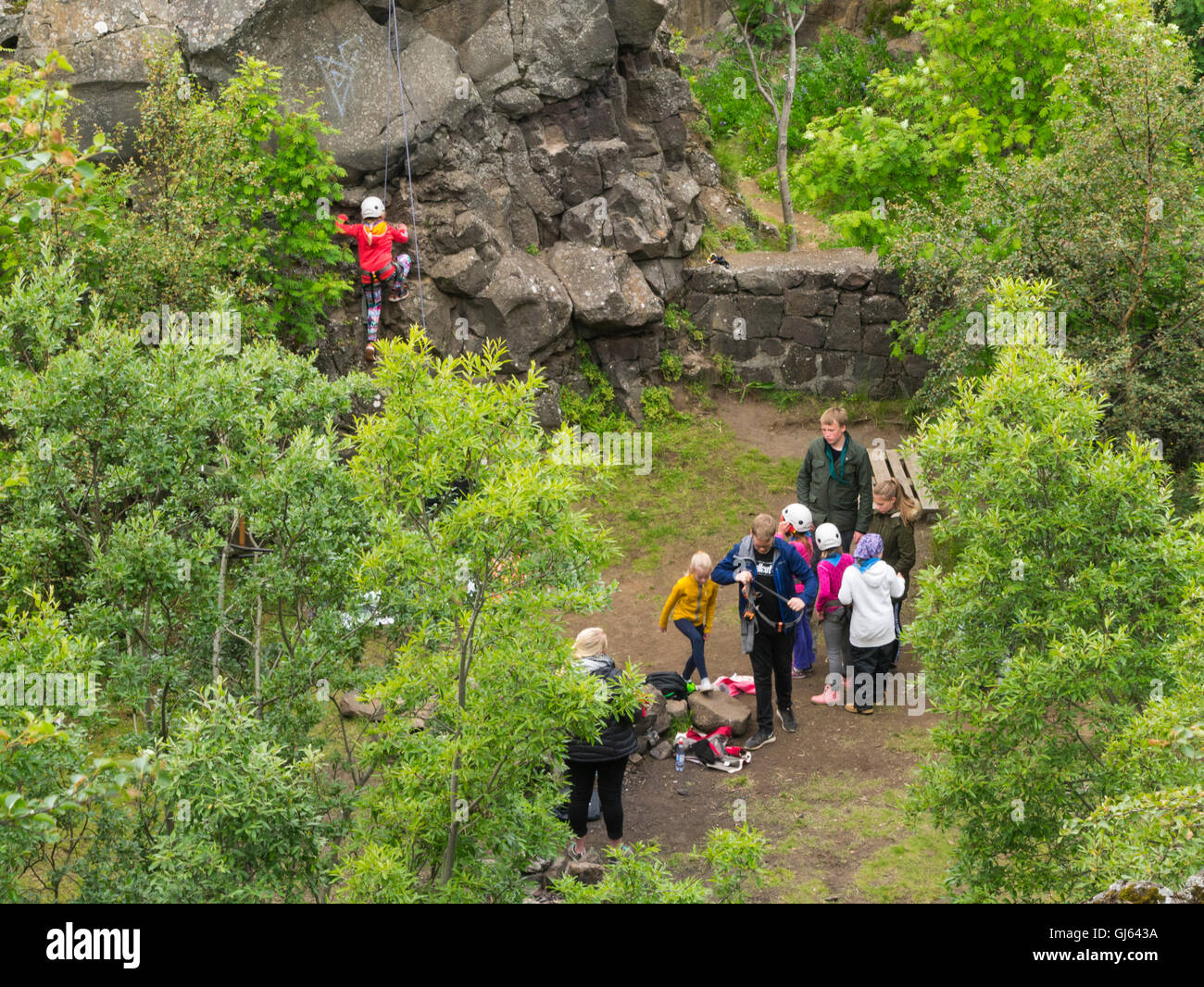 Gruppe von Schülerinnen und Schüler lernen, Felsen klettern kleine Mädchen, die Felswand Island helfende Lehrergruppe mit Sicherheitsausrüstung Reykjavik Seil festhalten Stockfoto