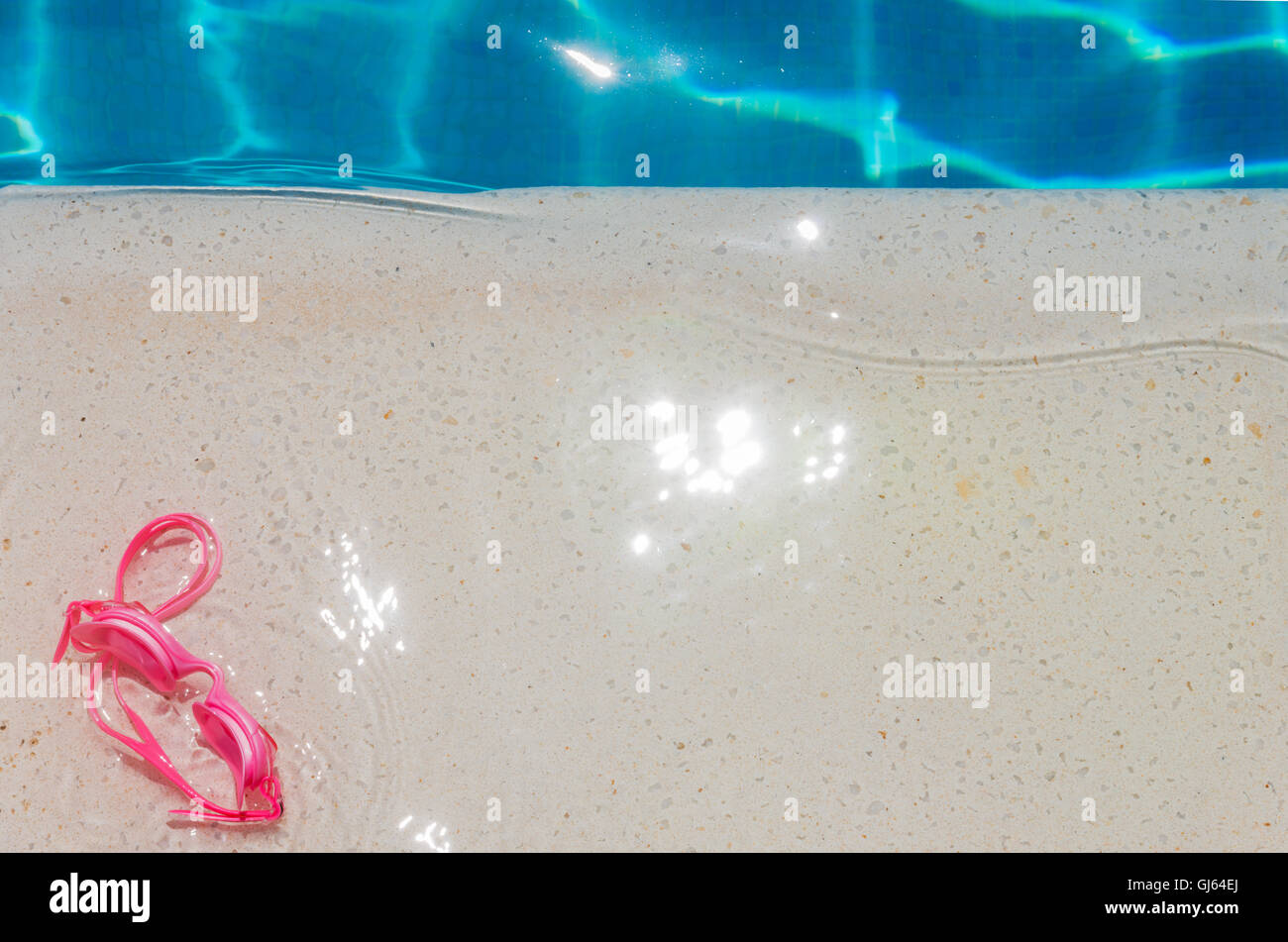 Ein paar Kinder Baby rosa Schwimmbrille auf Stein Marmor Schneide von einem kristallklaren blauen Pool mit Morgensonne Stockfoto