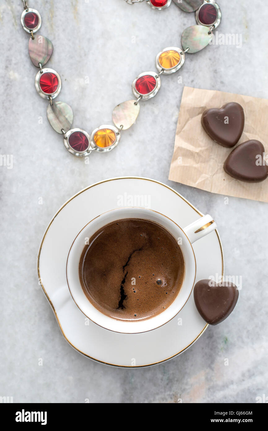 Tasse Kaffee, Halsketten und Schokolade auf Tisch, von oben Stockfoto