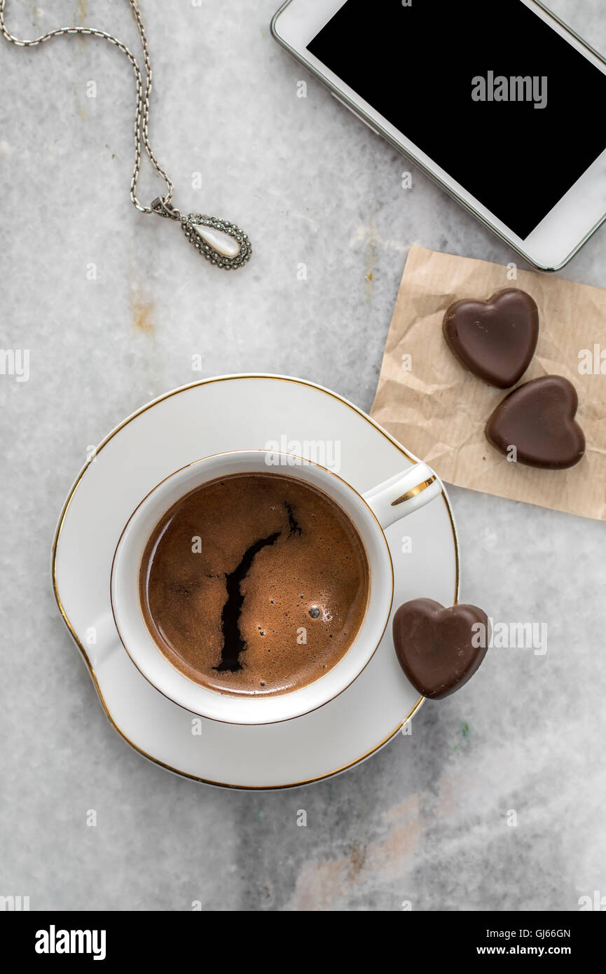 Tasse Kaffee, Halsketten und Schokolade auf Tisch, von oben Stockfoto