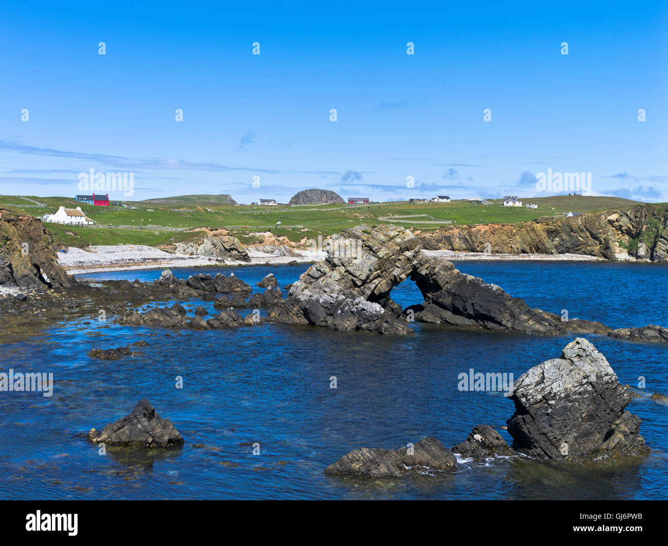 Dh South Harbor FAIR ISLE SHETLAND Sea arch im Bay Croft Cottage Häuser Felsenküste Schottland Stockfoto