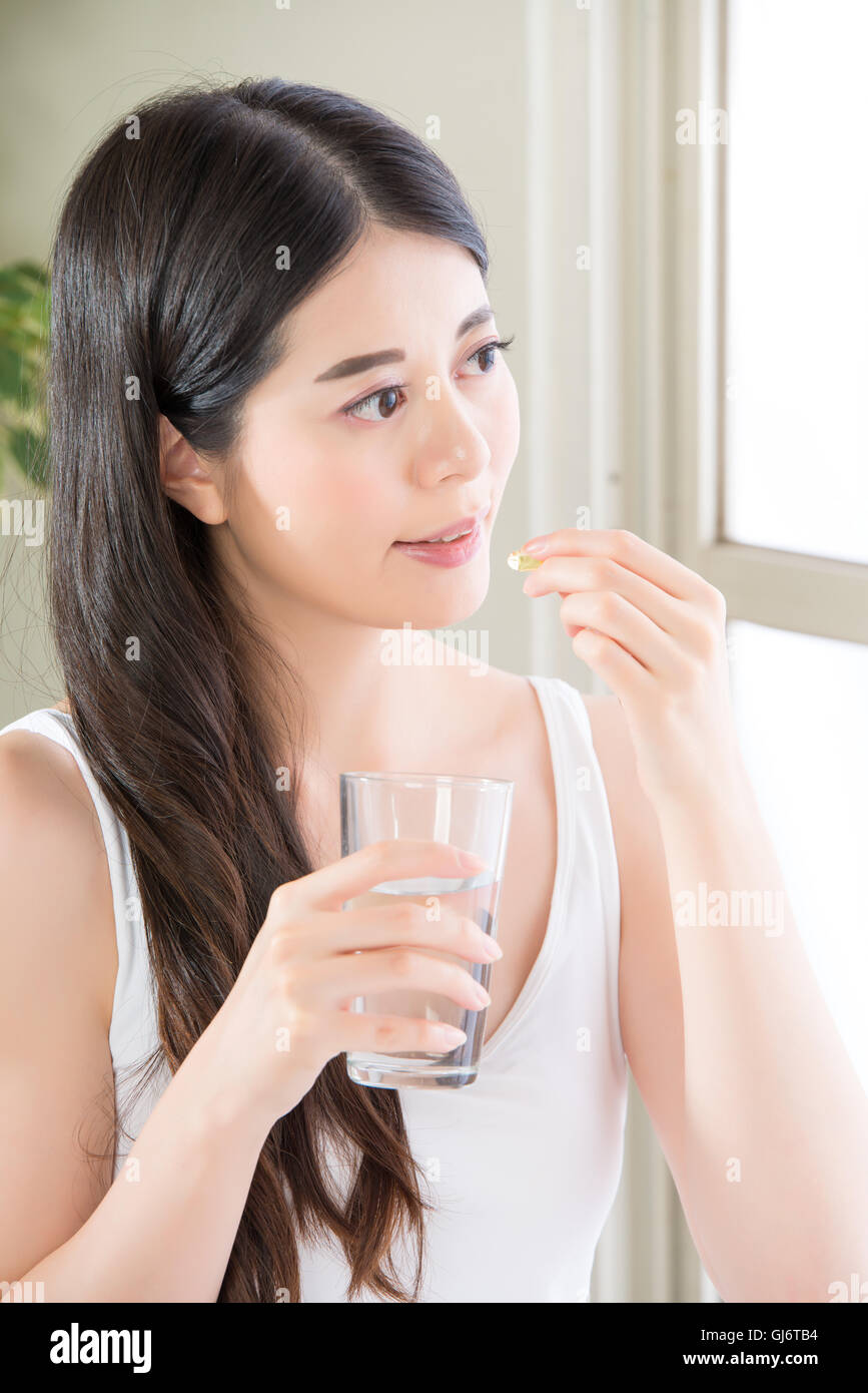 schöne asiatische Frauen Trinkwasser Nahrungsergänzung Pille zu Hause essen Stockfoto