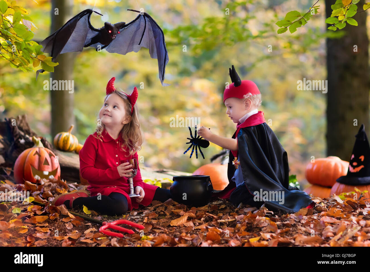 Zwei lustige Kinder tragen Teufel und Vampir Kostüm mit roten Hörnern und Trident Süßes oder Saures an Halloween. Stockfoto