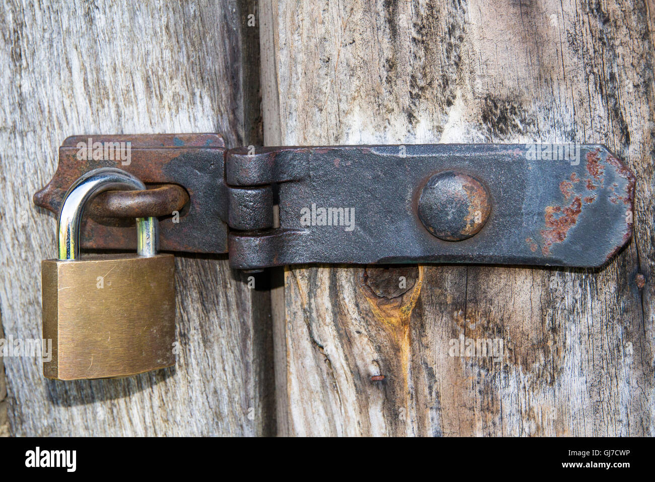 Nahaufnahme eines Vorhängeschlosses und altes Metall Hasp und Heften auf einer alten Holztür Stockfoto