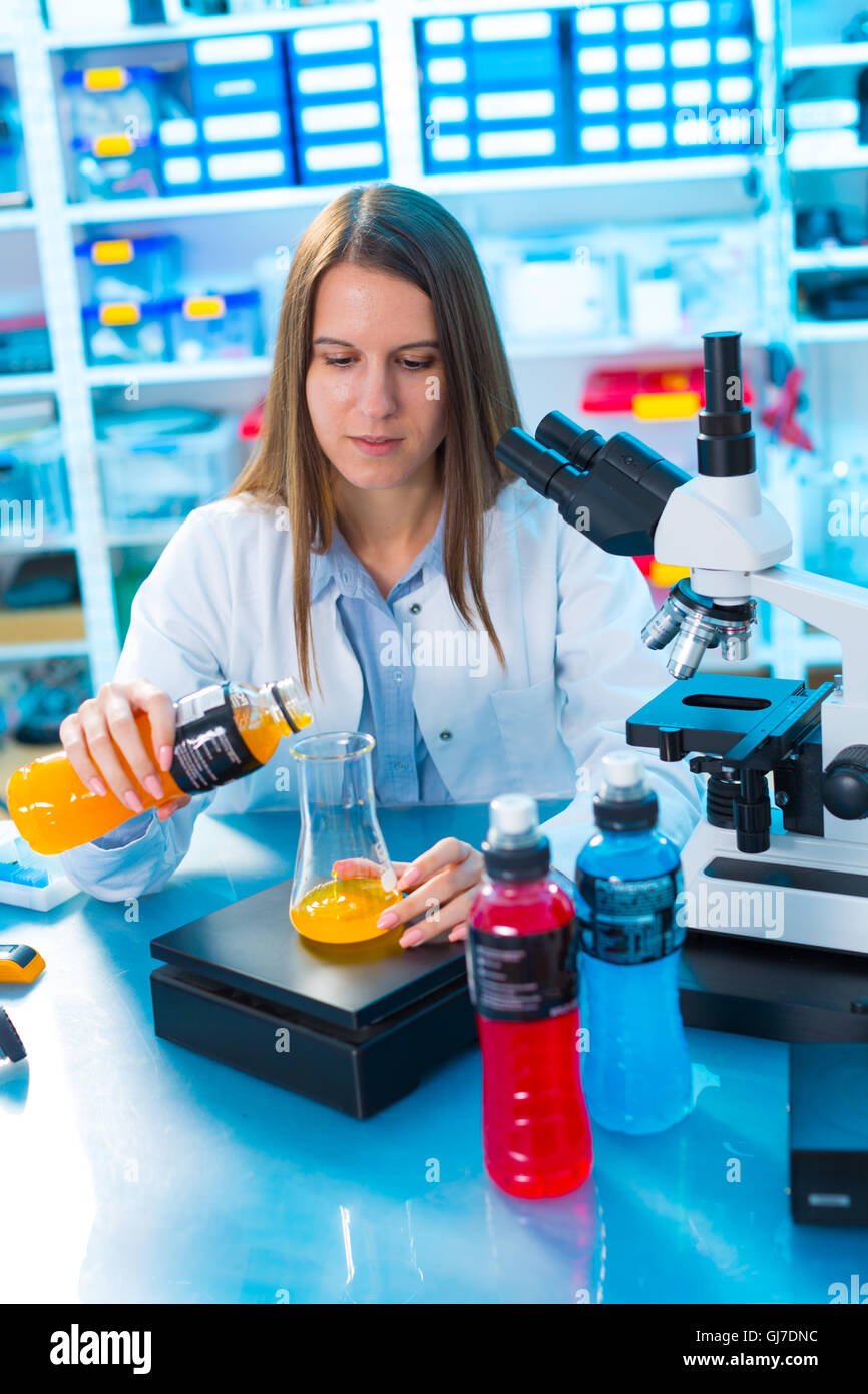 Qualitätskontrolle von Lebensmitteln. Junge Frau im chemischen Labor. Test der tragbaren Flasche Getränk Stockfoto