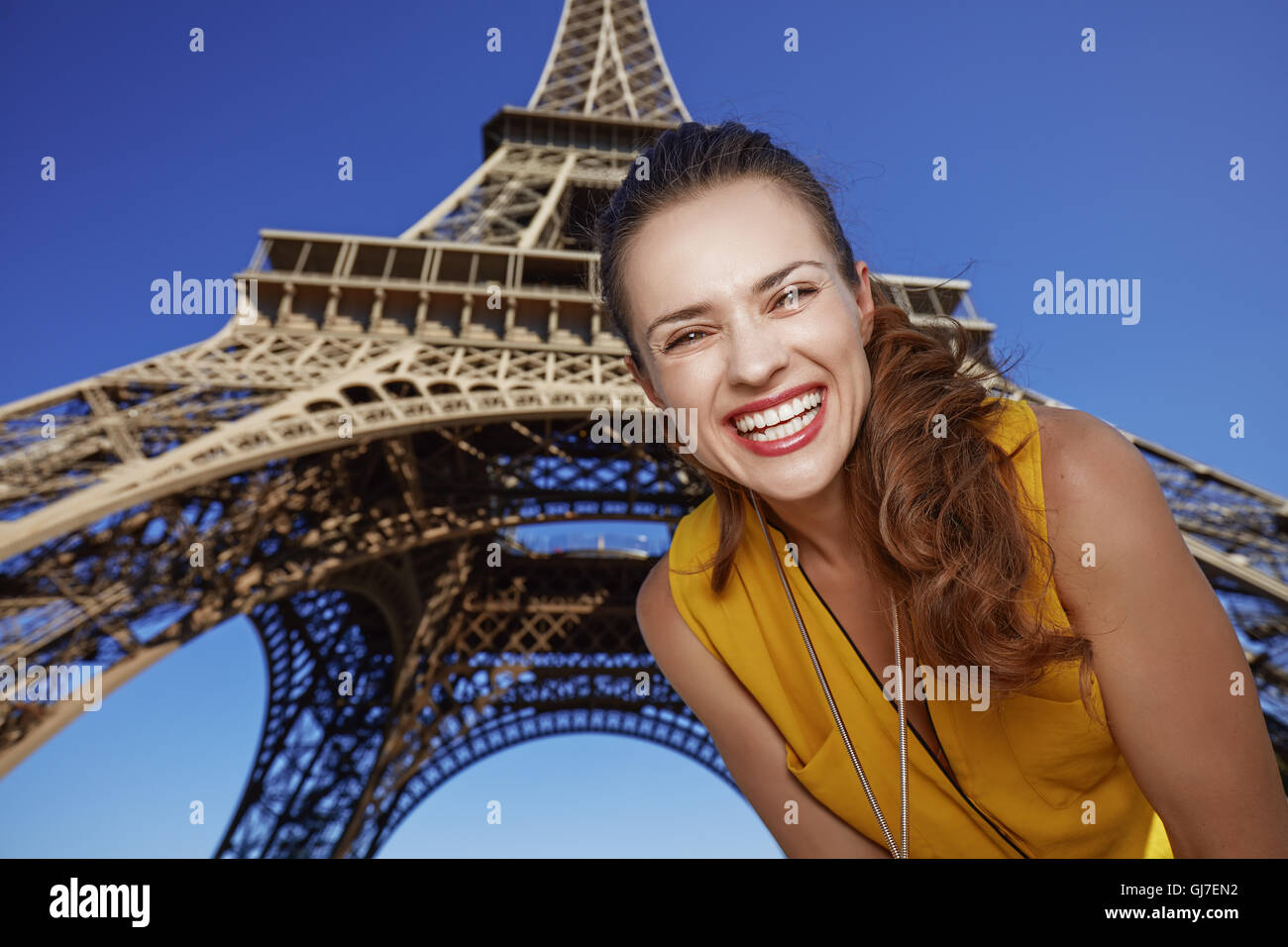 Touristisch, ohne Zweifel, aber noch nicht so viel Spaß gemacht. Porträt der lächelnde junge Frau an der Vorderseite Eiffelturm in Paris, Frankreich Stockfoto