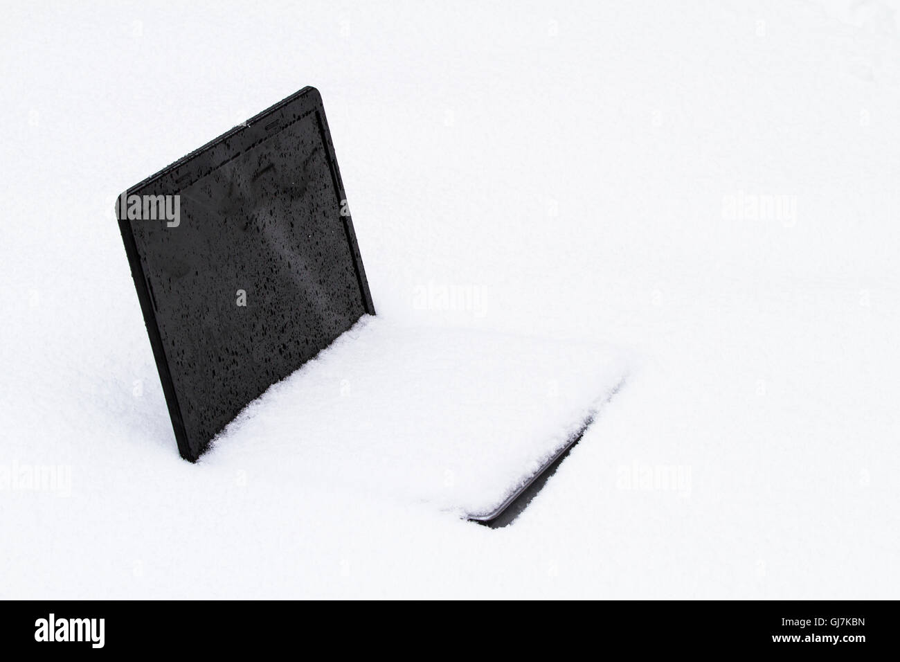 Eine gefrorene Laptop-Computer, die, den Hälfte in einer Schneeverwehung begraben Stockfoto
