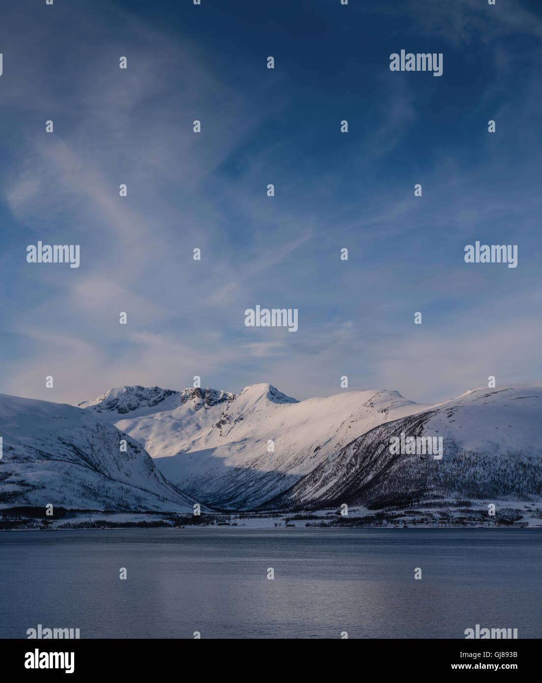 Farbbild des norwegischen Fjells im Winter mit Schnee bis in den Fjord, Troms, Norwegen. Stockfoto