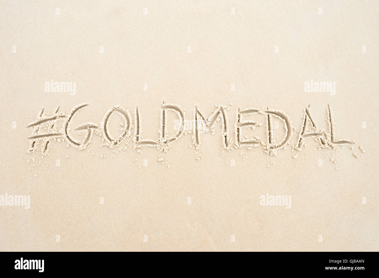 Hashtag-social Media-Nachricht für Goldmedaille geschrieben im Sand am Strand von Rio De Janeiro, Brasilien Stockfoto