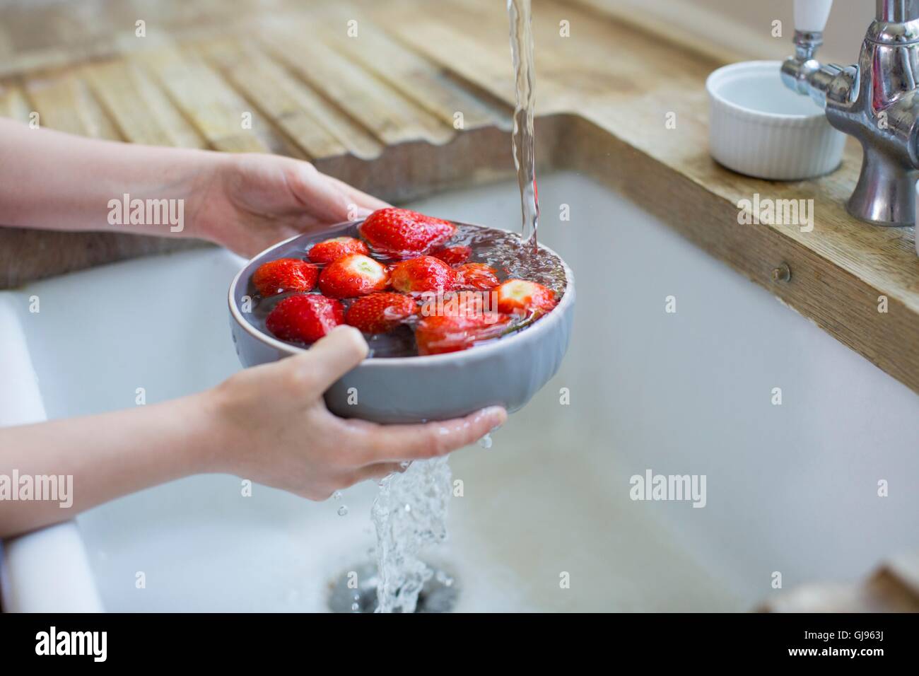 EIGENTUM FREIGEGEBEN. -MODELL VERÖFFENTLICHT. Mädchen, die frische Erdbeeren im Waschbecken zu waschen. Stockfoto