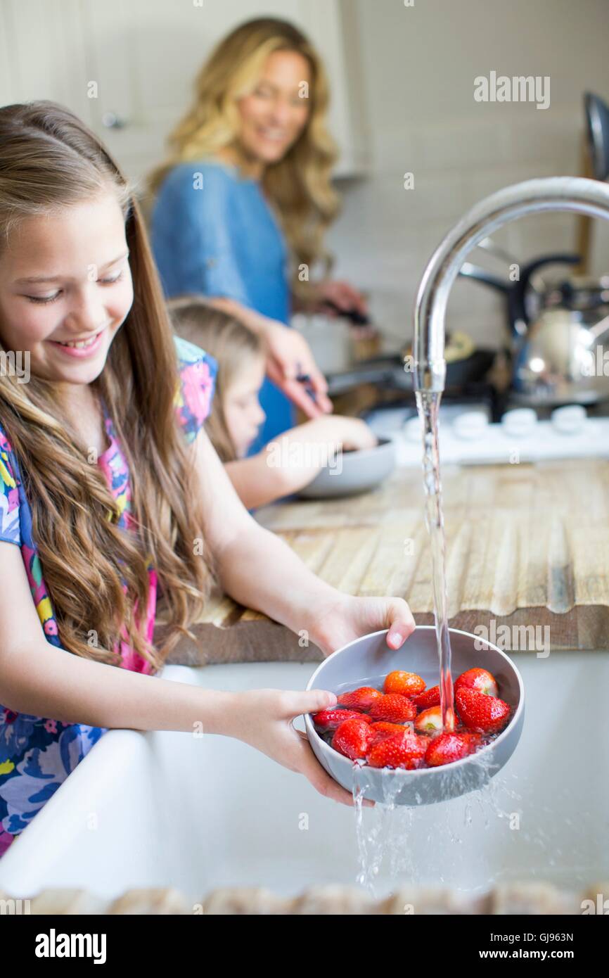 EIGENTUM FREIGEGEBEN. -MODELL VERÖFFENTLICHT. Mädchen, die frische Erdbeeren im Waschbecken zu waschen. Stockfoto