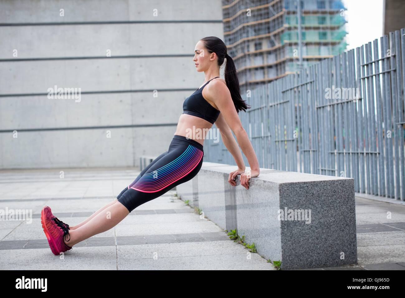 -MODELL VERÖFFENTLICHT. Junge Frau stretching auf Wand. Stockfoto