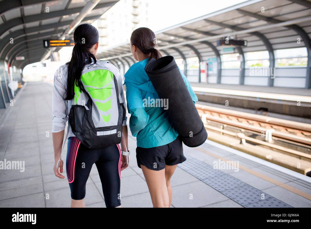 -MODELL VERÖFFENTLICHT. Zwei junge Frauen mit Sportgeräten auf Bahnsteig. Stockfoto