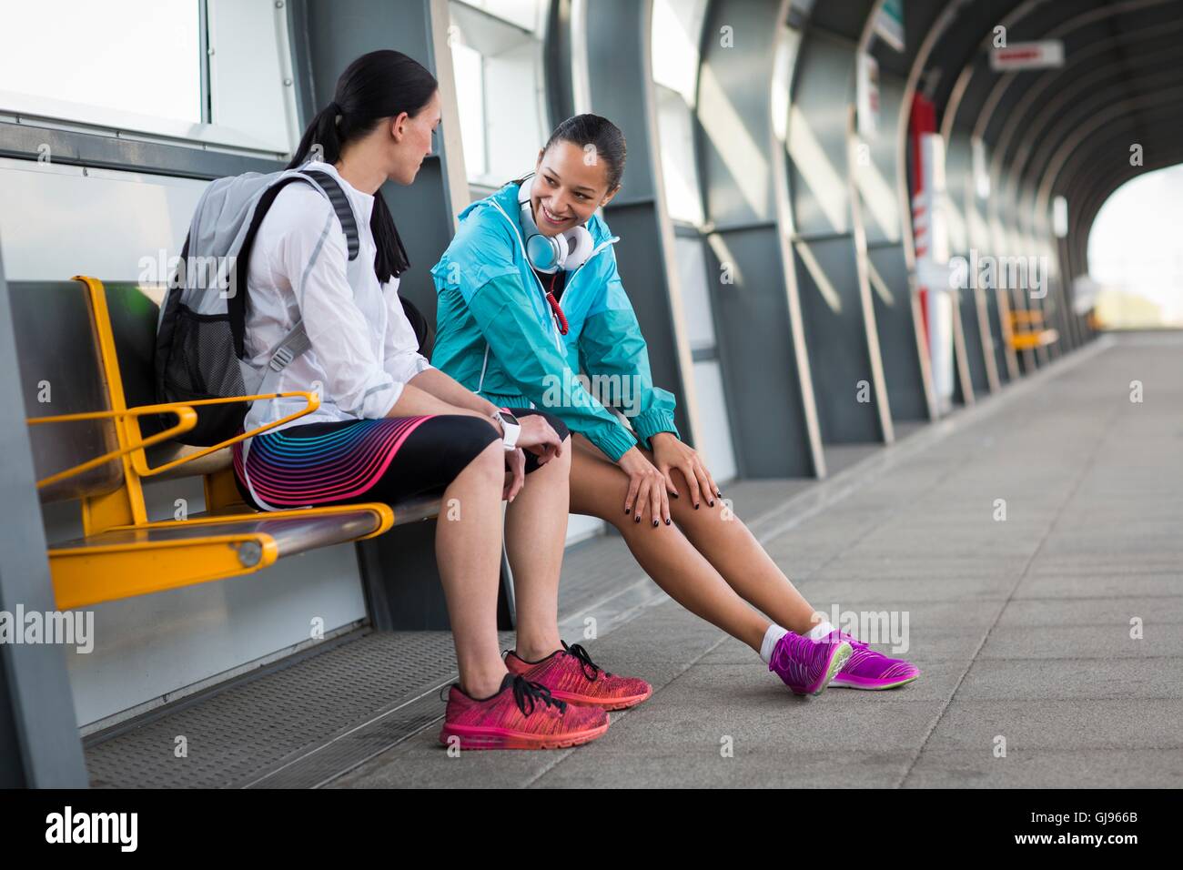 -MODELL VERÖFFENTLICHT. Zwei junge Frauen sitzen auf Bahnsteig. Stockfoto
