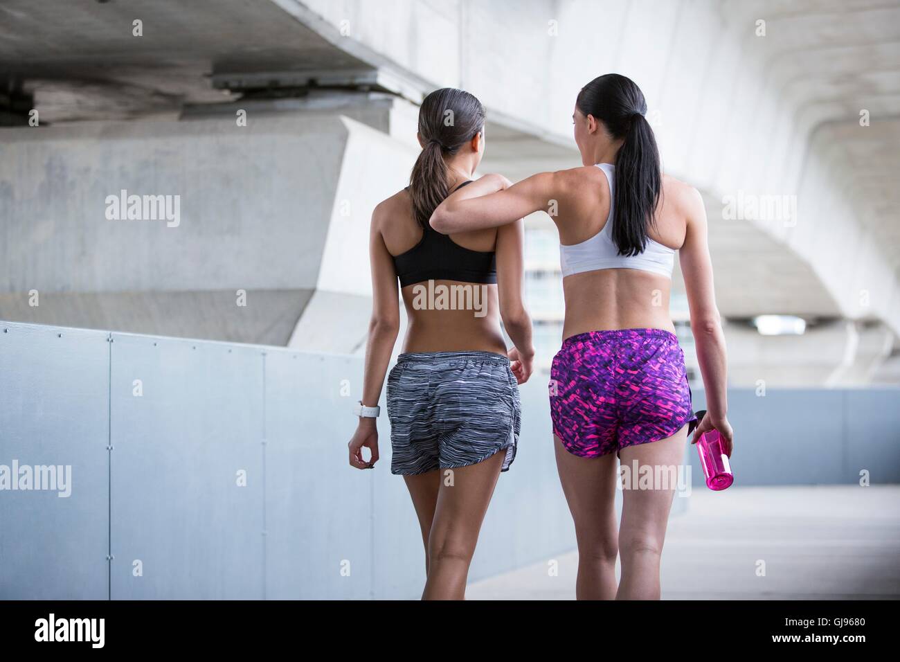 -MODELL VERÖFFENTLICHT. Zwei junge Frauen im Sport tragen zu Fuß entfernt. Stockfoto