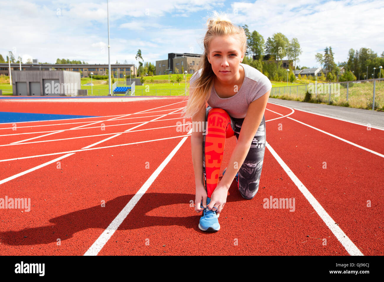 Athletische weibliche Läufer auf Laufstrecke Schnürsenkel zu binden Stockfoto