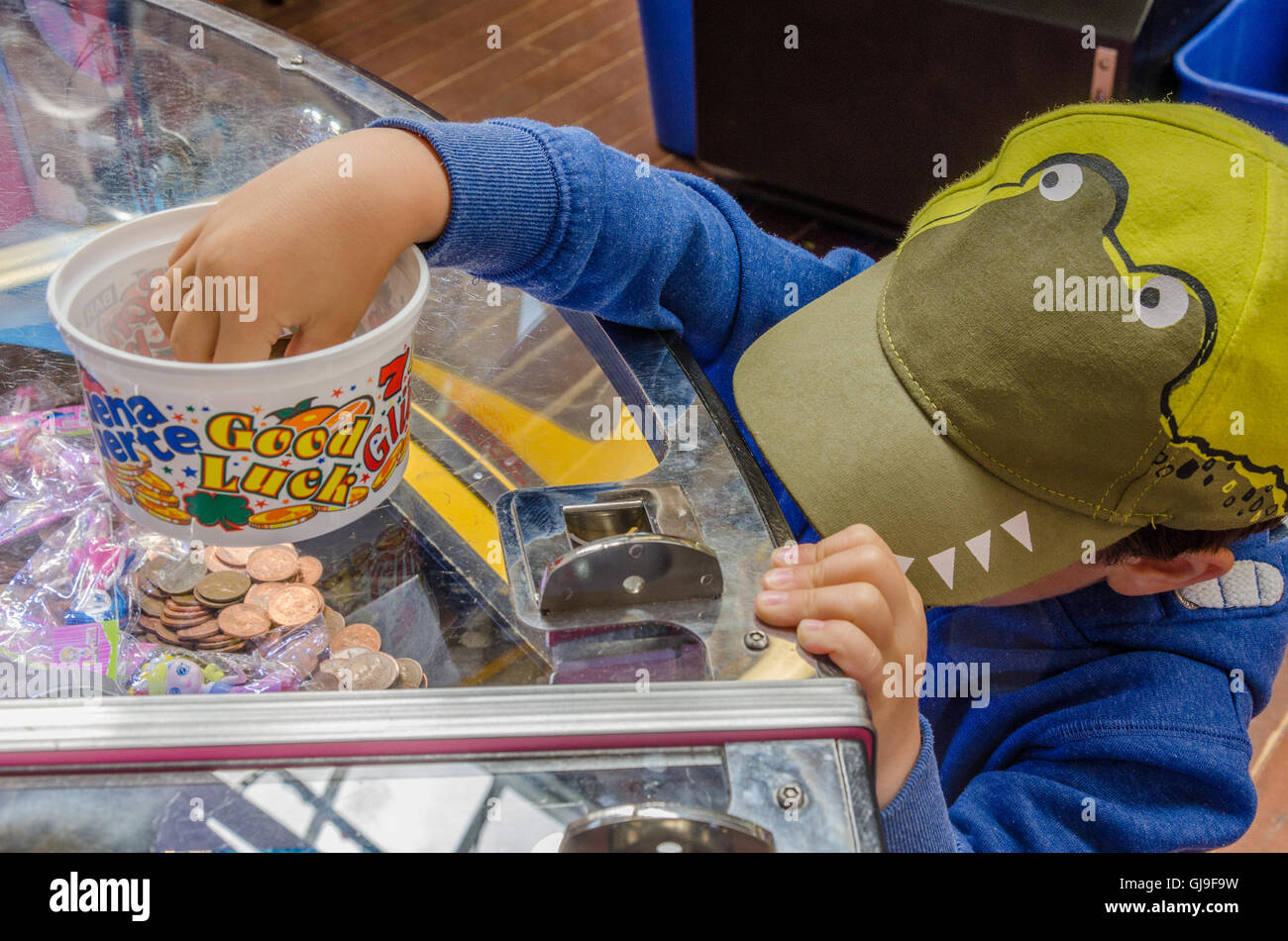 Ein kleiner Junge spielt auf einem 2P-Spielautomaten in einer Spielhalle in einem Ferienort. Stockfoto