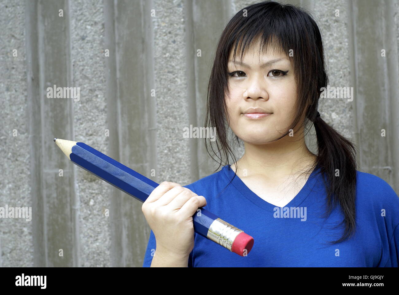 Junge Teen Asiatin in blau mit großen Bleistift, pädagogisches Konzept Stockfoto