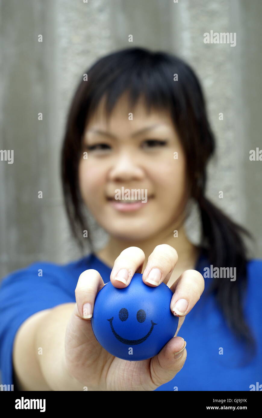 Junge asiatische Frau in blau mit Smiley-ball Stockfoto
